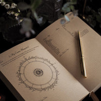 Open journal with astrological diagram and pen on a dark background