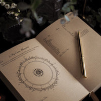 Open journal with astrological diagram and pen on a dark background