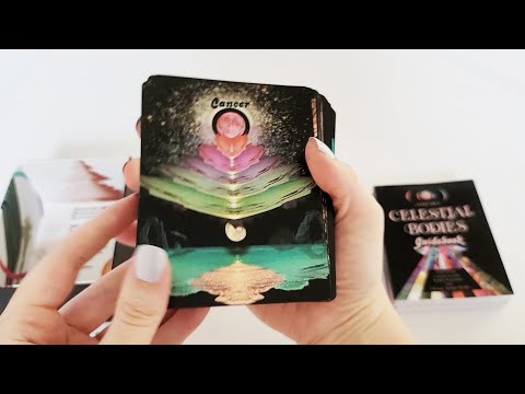 Unboxing of the Celestial Bodies Astrology and Numerology Oracle deck box by SERPENTFIRE (artist is Devany Amber Wolfe). Walkthrough of all the contents of the box and placing the box, stack of cards with back of cards shown and 2 guidebooks volume 1 and 2 from right to left.