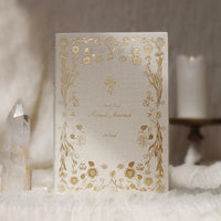 Decorative notebook with gold floral patterns on a soft white surface