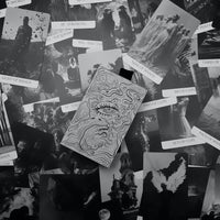 Collection of black and white cards from compos mentis tarot with various designs on a textured surface