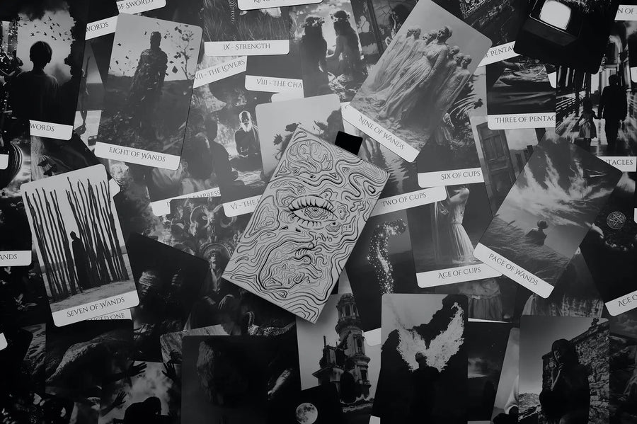 Collection of black and white cards from compos mentis tarot with various designs on a textured surface