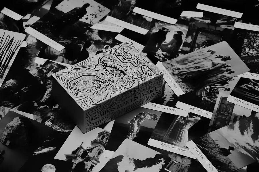 Collection of compos mentis tarot cards with intricate designs on a dark surface