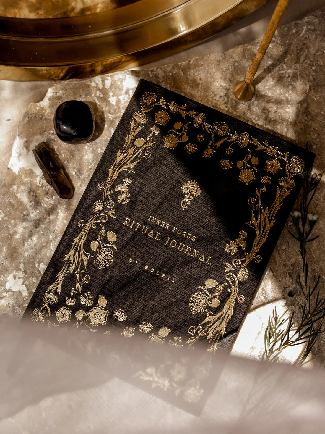 Decorative journal with gold text and designs on a textured surface with crystals.